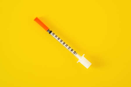 Empty insulin syringe on the yellow background, top view. Virus immunization and vaccination conceptの写真素材