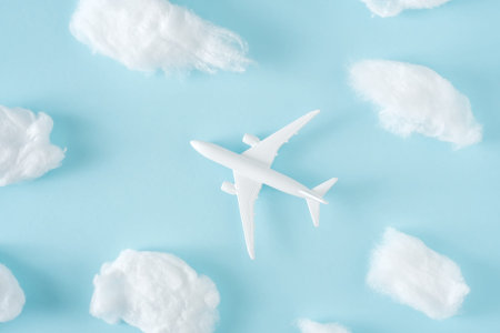 White jet airplane flying between the fluffy clouds. Travel around the world creative conceptの写真素材