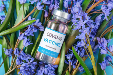 Springtime coronavirus Covid-19 medical vaccine concept with with vaccine vial lying on snowdrop...