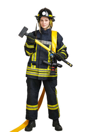 Full-length young brave woman in uniform and hardhat of fireman with fire hose on shoulders and sledgehammer in hands isolated on white background.の写真素材
