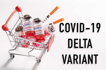 Wire shopping cart with vaccine vials bottles and syringes for vaccination against COVID-19 Delta variant strain coronavirus pandemic on white background, copy space for text, sale of vaccinesの写真素材