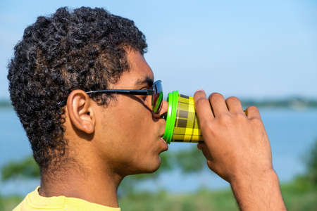 Young smiling Afro American sportsman holds soccer ball and showing his arm after receiving a vaccine at sunset in summerの写真素材
