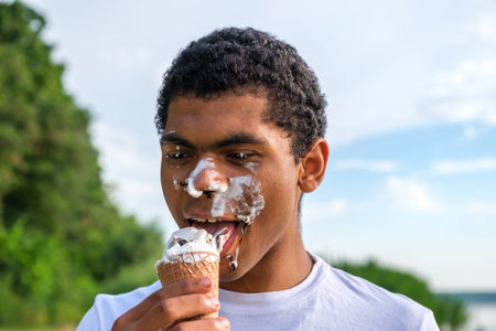Young smiling African American man holding Jack Russell terrier dog and coffee to go. Walking in...