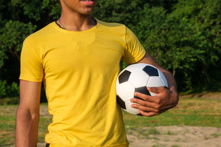 Soccer ball lying between bare feet of african american man on artificial soccer field outdoors in sunny park. Top view, copy spaceの写真素材