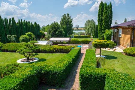 Beautiful backyard garden with nicely trimmed trees, bushes and stones. Landscape design. High quality photoの写真素材