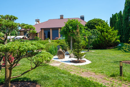 European style villa with pool and garden with nicely trimmed bushes and trees in front of the...