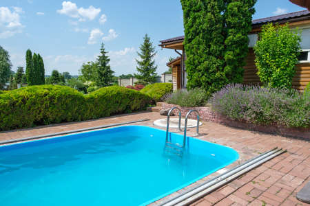 Swimming pool and garden with nicely trimmed bushes and stones in backyard. Landscape design. High quality photoの写真素材