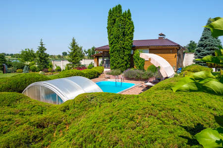 Garden with nicely trimmed bushes and stones and swimming pool in backyard. Landscape design. High quality photoの写真素材