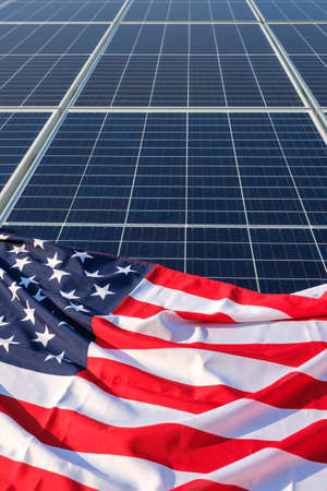 American flag close up placed on solar panels on solar power plant, an ecological alternative source of electricity, copy space, vertical orientationの写真素材