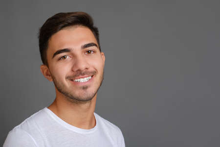 Close-up portrait of handsome smiling guy on gray background. High quality photo, copy spaceの写真素材