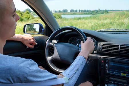 Prosthetic amputated arm of a Caucasian man on the steering wheel who drives a car on a sunny summer dayの写真素材