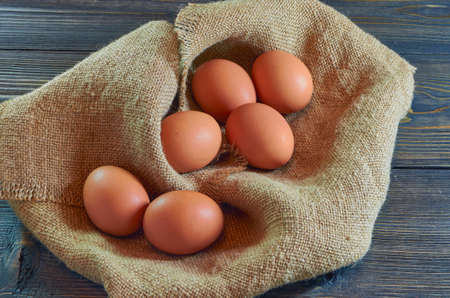 Chicken eggs on a burlap napkin on a dark wooden backgroundの写真素材