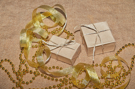 Christmas boxes in craft paper lie on the table, decorated with gold ribbons and beads. Christmas...