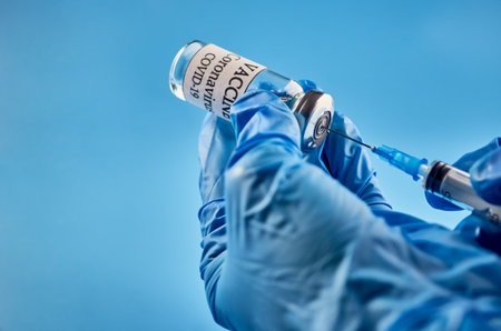 A bottle of COVID-19 vaccine and a syringe with an injection needle against coronavirus infection in...