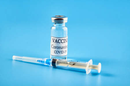 Coronavirus vaccine: a syringe and a bottle on a blue background. The concept of immunization and vaccination. Copyspace.の写真素材
