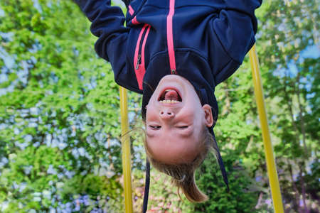 Happy funny girl plays in the playground. A child does sports exercises on the stairs in the street. A teenager sports on the street. View from below.の写真素材