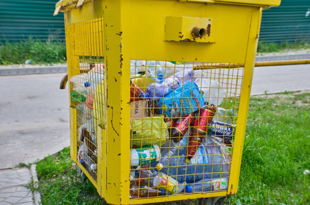 Russia, Vladimir, 02.06.2021, Yellow container for household garbage filled with garbage stands on...