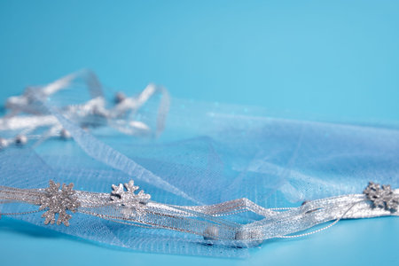 Christmas decoration on a blue background. Silver ribbon and silver beads lie on the fabric....