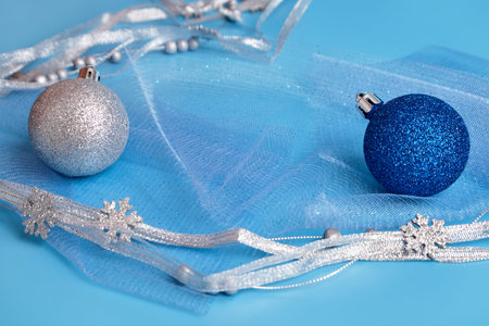 Christmas holiday background. Selective focus. Silver and blue balls, silver ribbon on a blue background. Greeting Christmas card. A place to copyの写真素材