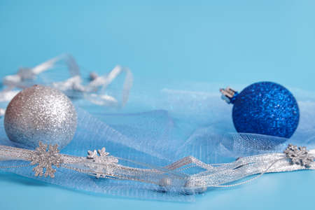 Christmas holiday background. Selective focus. Silver and blue balls, silver ribbon on a blue background. Greeting Christmas card. A place to copyの写真素材