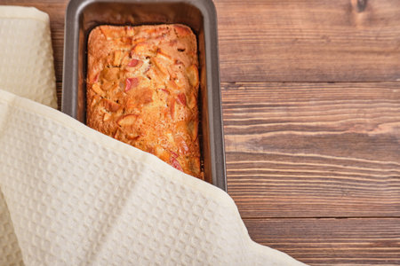 Apple pie in a baking tray on a brown wooden table. Apple charlotte. Homemade apple pie. Close-up,...