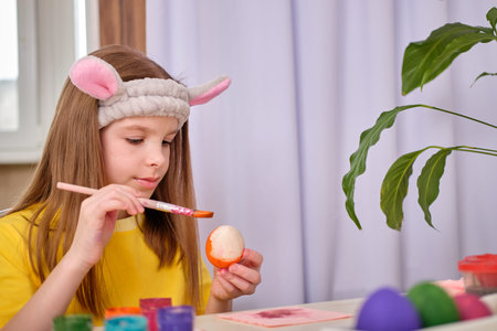 A girl paints Easter eggs with paints. Portrait of caucasian girl, child 9-10 years old decorating...