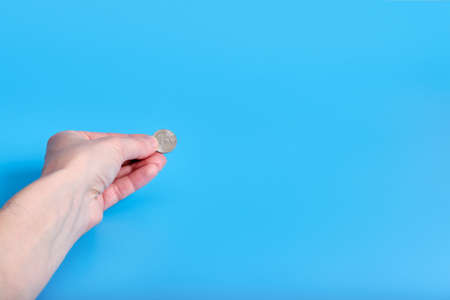 Russian ruble money, coins in a female hand on a blue background. Copy spaceの写真素材