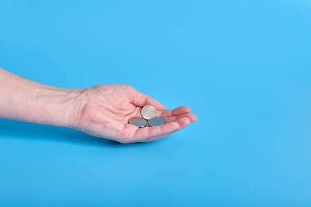 Russian ruble money, coins in a female hand on a blue background. Copy spaceの写真素材
