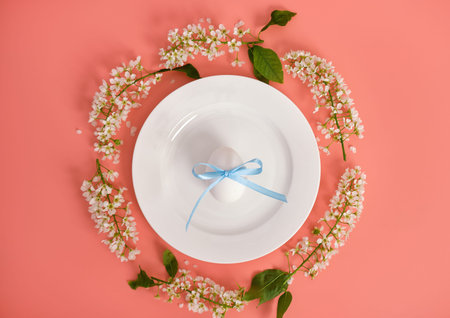 Easter composition. Easter eggs on a white plate, cherry branches in the shape of a circle. Pink...
