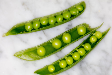 Fresh green peas closeup on a marble backround