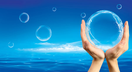 Hands holding a bubble with spashes inside against an ocean background