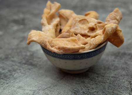 Traditional Polish sweets called faworki or chrust in Polish clsoe up in small bowl on stony tableの写真素材