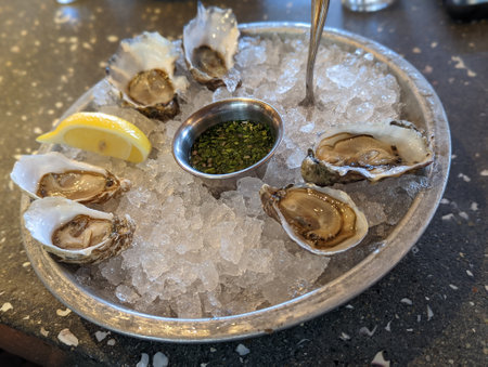 Fresh oysters on ice with lemon and herbs in a restaurant.の写真素材