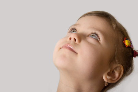Little white girl look up, gray backgroundの写真素材