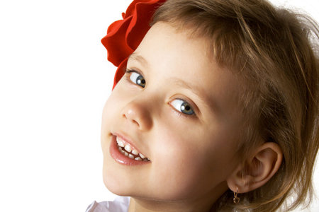 Little smiling girl with red rouses in the hairの写真素材