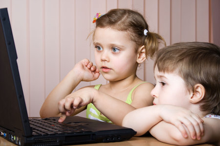 little girl and little boy working with a laptopの写真素材