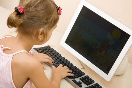 Little girl typing text at the home computer