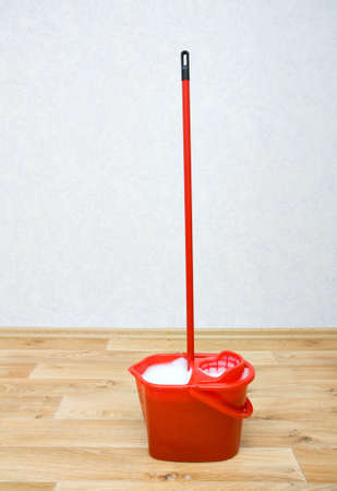 A red mop in a plastic bucket on floorの写真素材