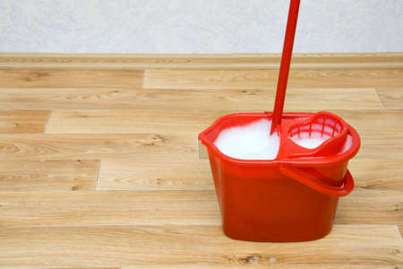 A red mop in a plastic bucket on floorの写真素材