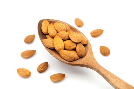 almonds on white fund with a wooden spoonの写真素材