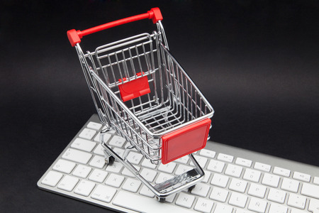 shopping cart and computer on black keyboardの写真素材