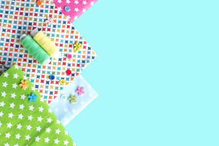 Multi-colored cotton fabrics, buttons in the form of flowers and round, yellow and green bobbins of...