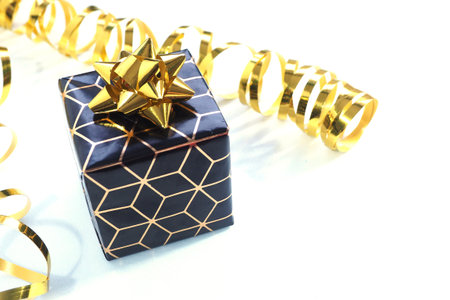 black and gold gift box with a gold bow and gold serpentine on a white background.