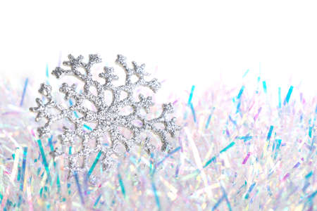 Silver shiny snowflake on blue and white tinsel on a white background.の写真素材