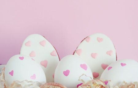 Easter white eggs with pink hearts, gingerbread in the form of eggs with hearts on a pink...
