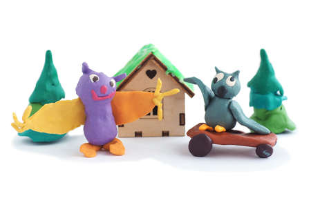Plasticine figures of an owl on a skateboard and a bat, Christmas trees and a house. Isolate on a white background.の写真素材