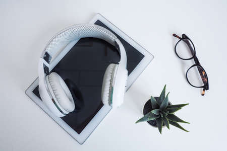 white wireless on a white tablet, glasses and a flower on a white table. wilde on top. concept podcast, audiobooks, online learning.の写真素材