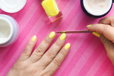 female hands on a bright pink background doing a manicure.の写真素材