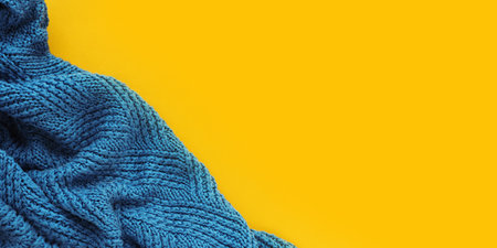autumn banner blue knitted plaid with folds on a mustard yellow background.