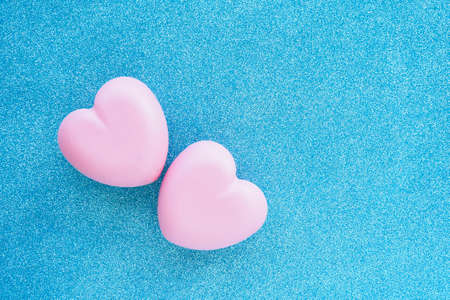 two pink glittering hearts on a blue glittering background. copy space.の写真素材